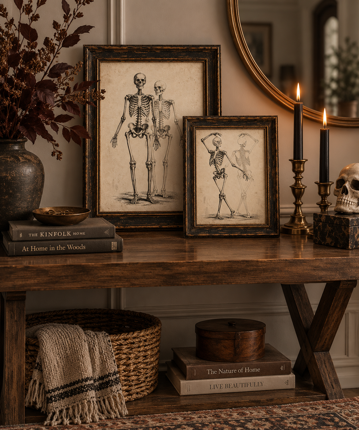 Two framed vintage-style skeleton illustrations displayed on a rustic wooden console table, surrounded by candles, books, a basket, and dried flowers in a cozy interior setting.
