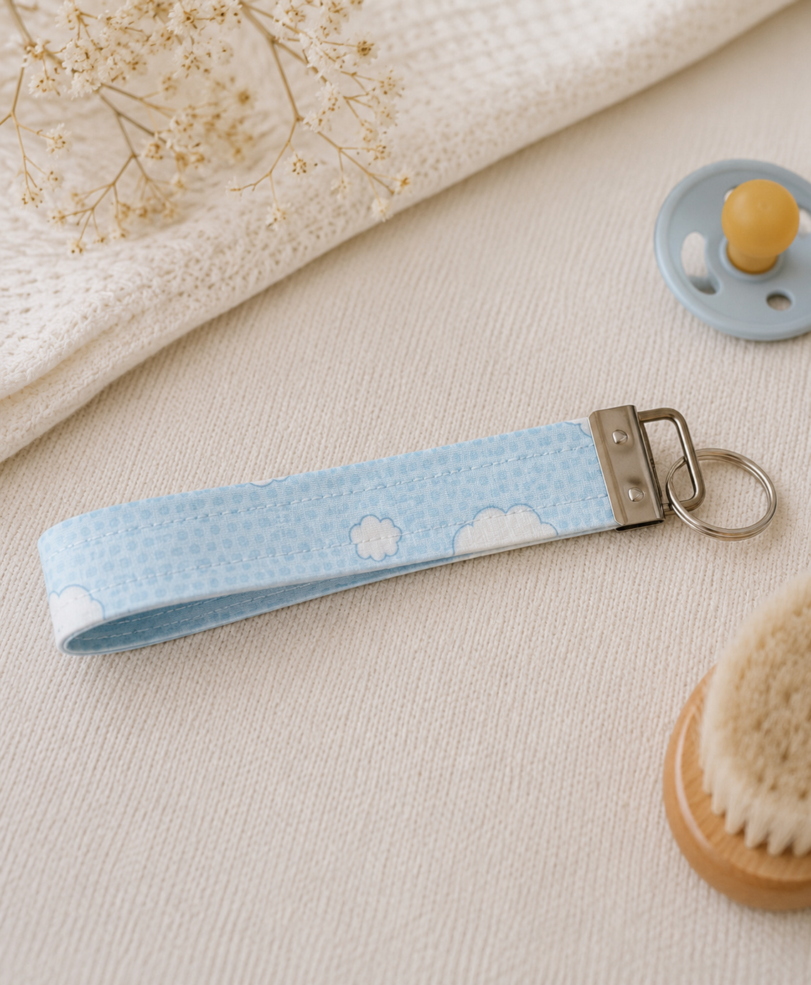 Blue Skies quilted key fob wristlet with soft blue cloud print, styled with nursery-inspired everyday essentials.