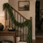 faux cedar garland styled on a modern holiday mantel with brass candlesticks, knit stockings, and neutral Christmas décor.