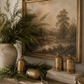 Antique gold holiday bells in assorted sizes styled on a reclaimed wood console with cedar garland, vintage landscape artwork, stoneware vase, and warm designer holiday décor.