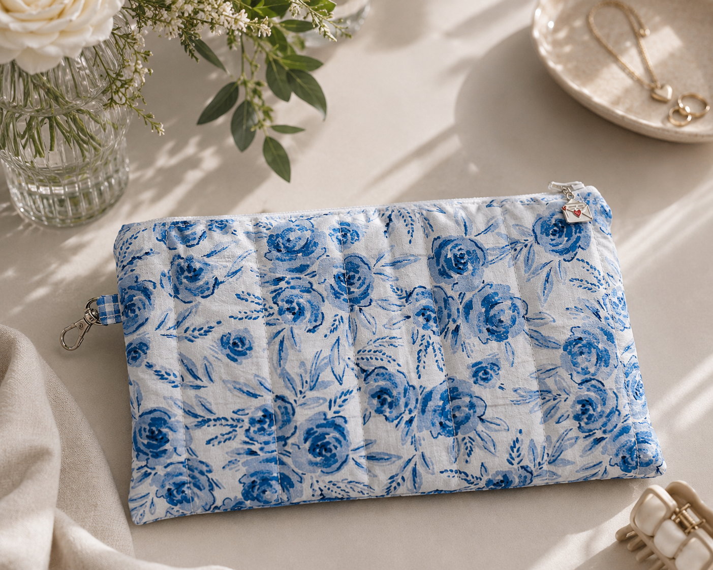 Blue Blossom quilted large wristlet pouch styled with everyday essentials on a modern marble tabletop in a soft editorial setting.