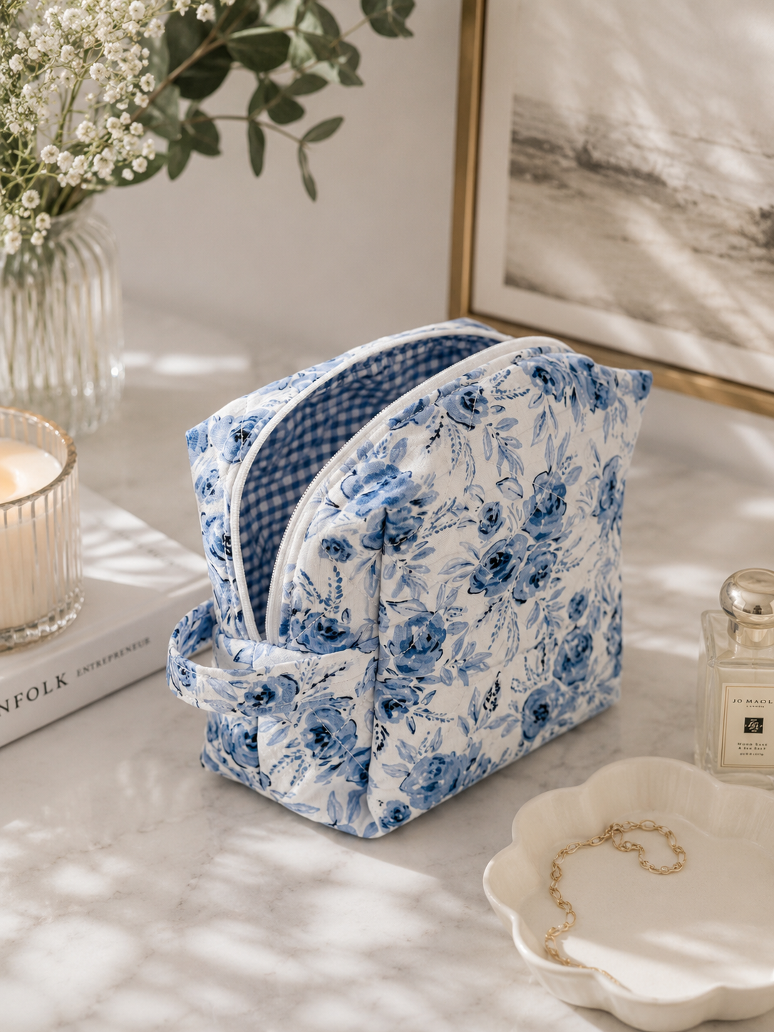 Blue Blossom quilted makeup bag styled on a vanity with beauty essentials in a bright editorial lifestyle setting.