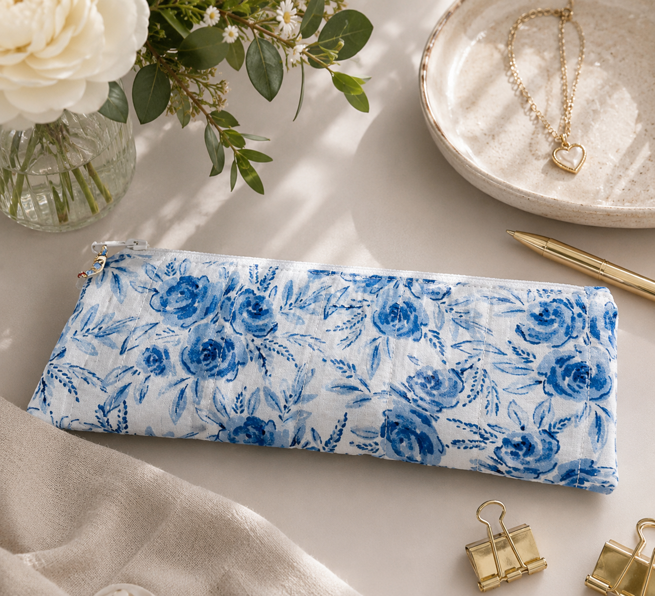 Blue Blossom quilted pencil pouch styled on a clean workspace with stationery and modern desk accessories.
