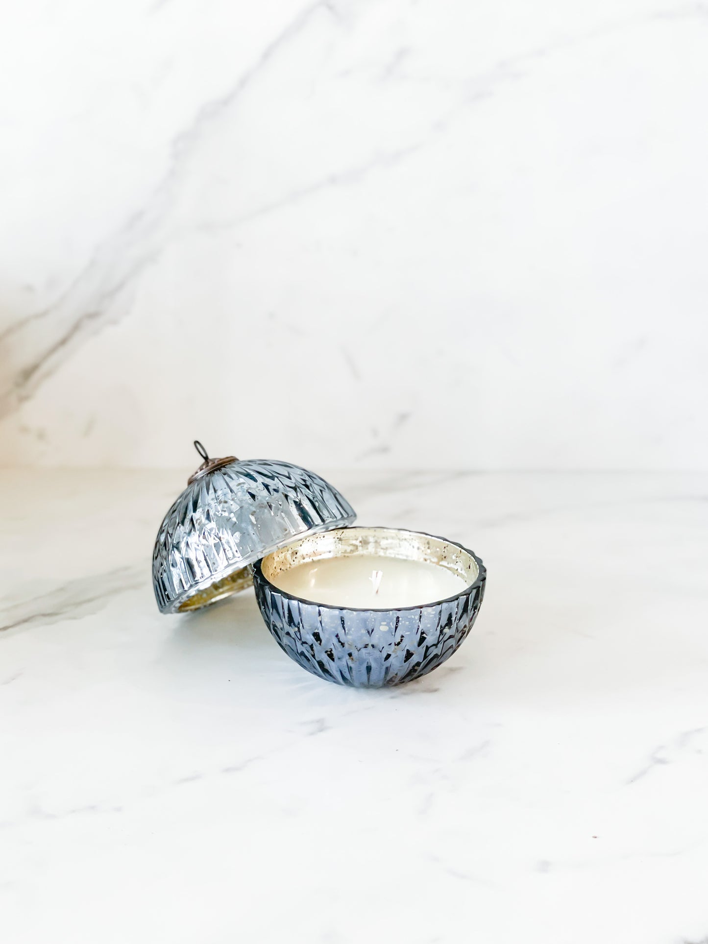 Blue ornament candle with citrus, fir, black currant, white birch, and ebony woods fragrance