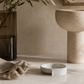 Minimal cement soap dish styled on creamy marble with warm brass accents, olive branches, smoked glass, and spa-inspired California modern decor.