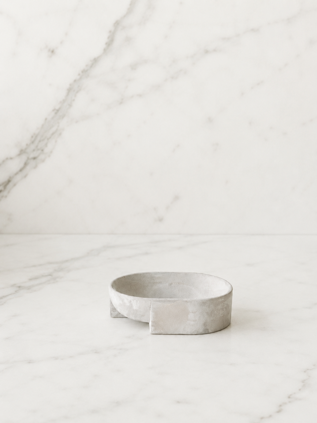 Minimal handcrafted cement soap dish on a clean white marble surface with soft neutral lighting and modern luxury studio styling.