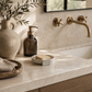 Luxury spa vanity scene featuring a handmade cement soap dish styled with linen towels, olive branches, and warm marble surfaces.
