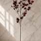 Dark red faux maple leaf stem displayed against a white marble studio backdrop, highlighting its natural branching, rich burgundy leaves, and realistic texture.