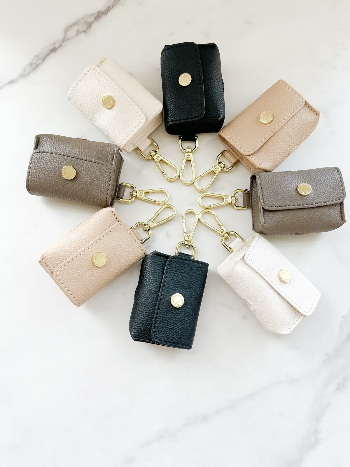 Evie Clip On AirPoad Cases circled around on a marble counterop displaying all the colors.