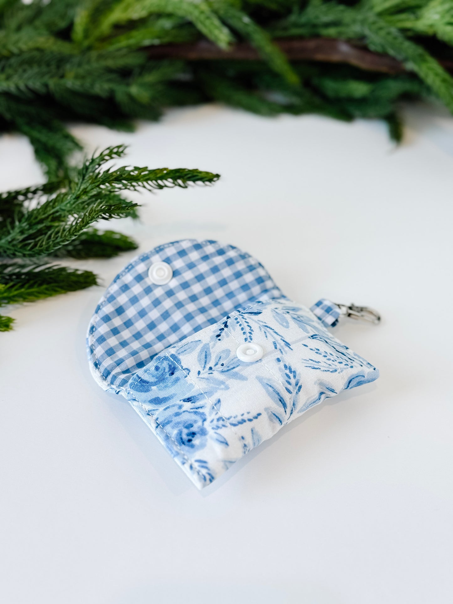 Gingham blue lined airpods case with floral blue blossom exterior.