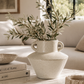 Speckled ivory ceramic vase with olive branches styled on marble coffee table in warm neutral California coastal living room