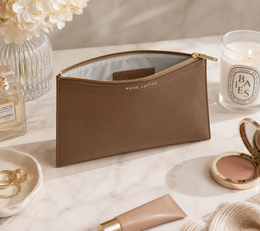 Katie Loxton Cleo Pouch in Mink faux leather styled on a marble vanity with luxury beauty essentials, jewelry, and elegant neutral décor.