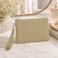 Katie Loxton Zana Wristlet Pouch in Sage Green faux leather styled on a luxury marble vanity with delicate gold jewelry, baby's breath, and elegant neutral décor.
