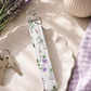 Lavender Meadows floral key fob wristlet with purple gingham accent styled with keys, sunglasses, and a neutral handbag.