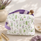 Lavender Meadows quilted makeup bag with wildflower print and purple gingham lining styled on a vanity with everyday beauty essentials.