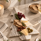 Tree-shaped gray and white marble cheese board styled with cheese, crackers, grapes, olives and rosemary for holiday entertaining.