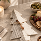 Gray and white marble Christmas tree cheese board with wooden spreader styled on a neutral kitchen countertop for holiday entertaining.