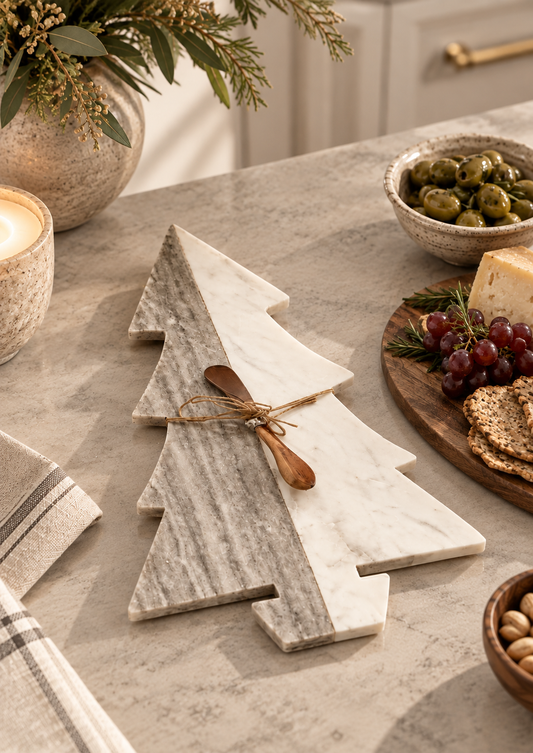 Gray and white marble Christmas tree cheese board with wooden spreader styled on a neutral kitchen countertop for holiday entertaining.