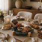Round green marble serving board with mango wood stand styled as a charcuterie centerpiece on a modern dining table with artisan cheeses, cured meats, crackers, olives, wine glasses, candles, and neutral table décor.