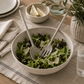 Matte gray stainless steel salad servers styled in a ceramic salad bowl with fresh greens on a modern California-inspired tablescape.