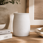 Handcrafted matte white ceramic vessel styled with artichokes and neutral decor on travertine surface in luxury coastal interior