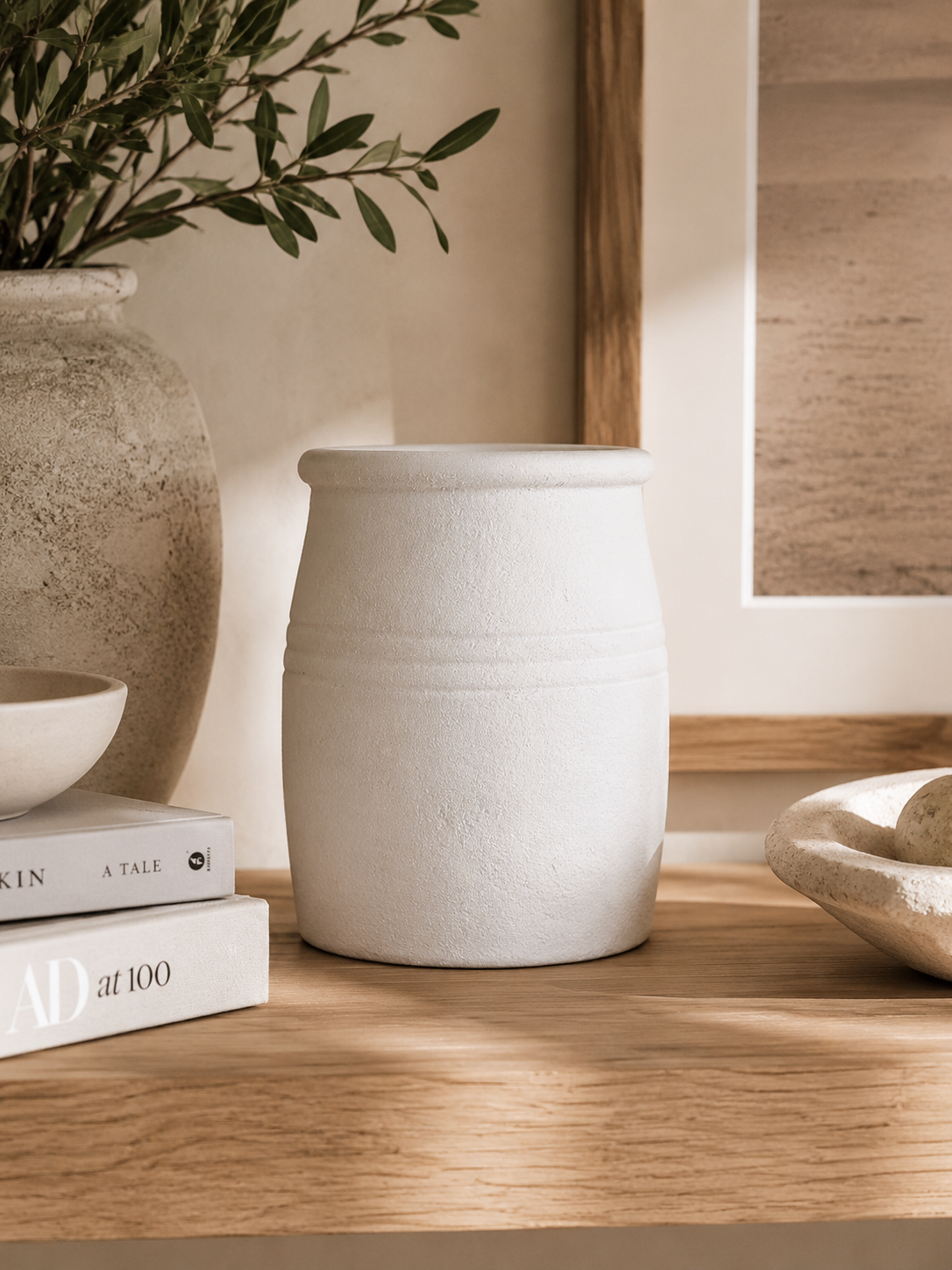 Handcrafted matte white ceramic vessel styled with artichokes and neutral decor on travertine surface in luxury coastal interior