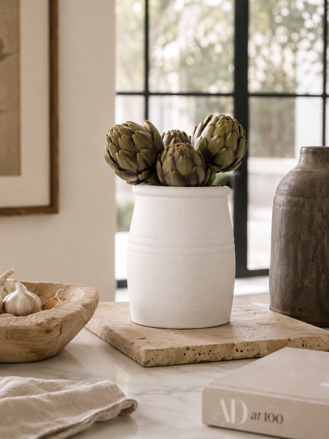 Matte white ceramic vessel styled with wooden kitchen utensils in warm California coastal modern kitchen