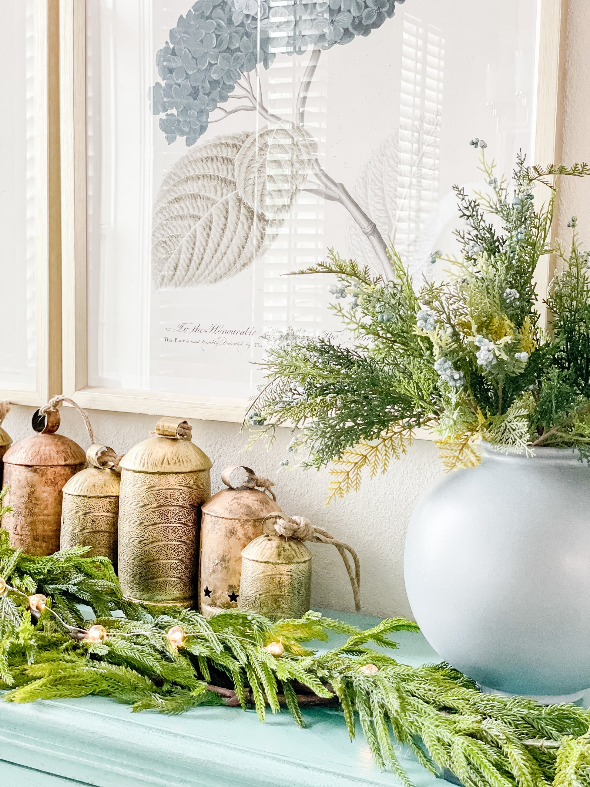 Real Touch Norfolk Pine garland styled on mantel with gold bells and winter greenery