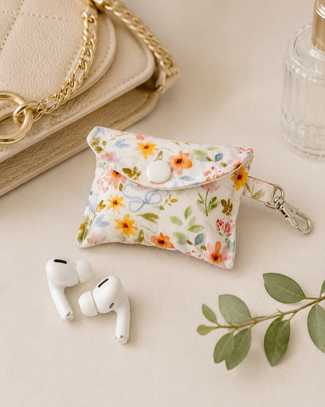 Petals & Posies quilted AirPods case with floral print and coordinating lining styled on a marble tray with wireless earbuds.