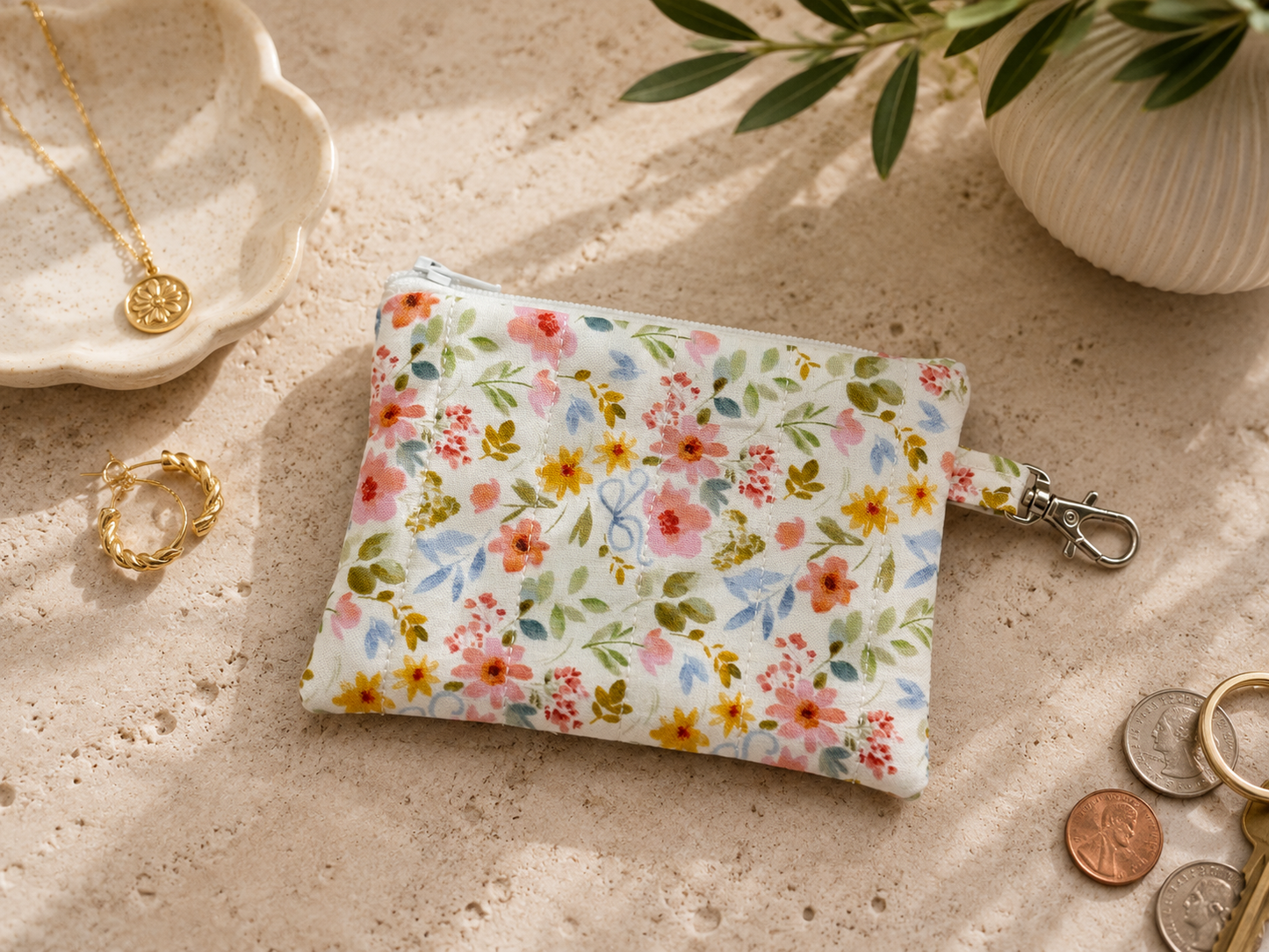 Petals & Posies quilted coin purse with floral print styled with coins and everyday carry essentials on a neutral tabletop.