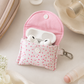 Pink floral quilted AirPods case styled with beauty products and feminine accessories in soft neutral lighting