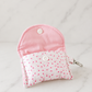 Pink floral quilted AirPods case with snap closure on neutral marble studio background