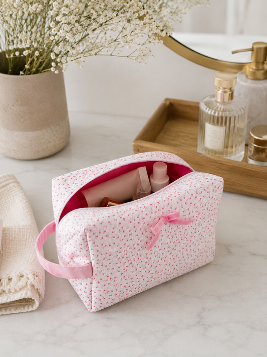 Pink floral makeup bag styled with beauty essentials on luxury bathroom countertop in soft natural light