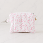 Pink floral quilted coin purse with silver zipper and heart charm on white marble background in soft studio lighting
