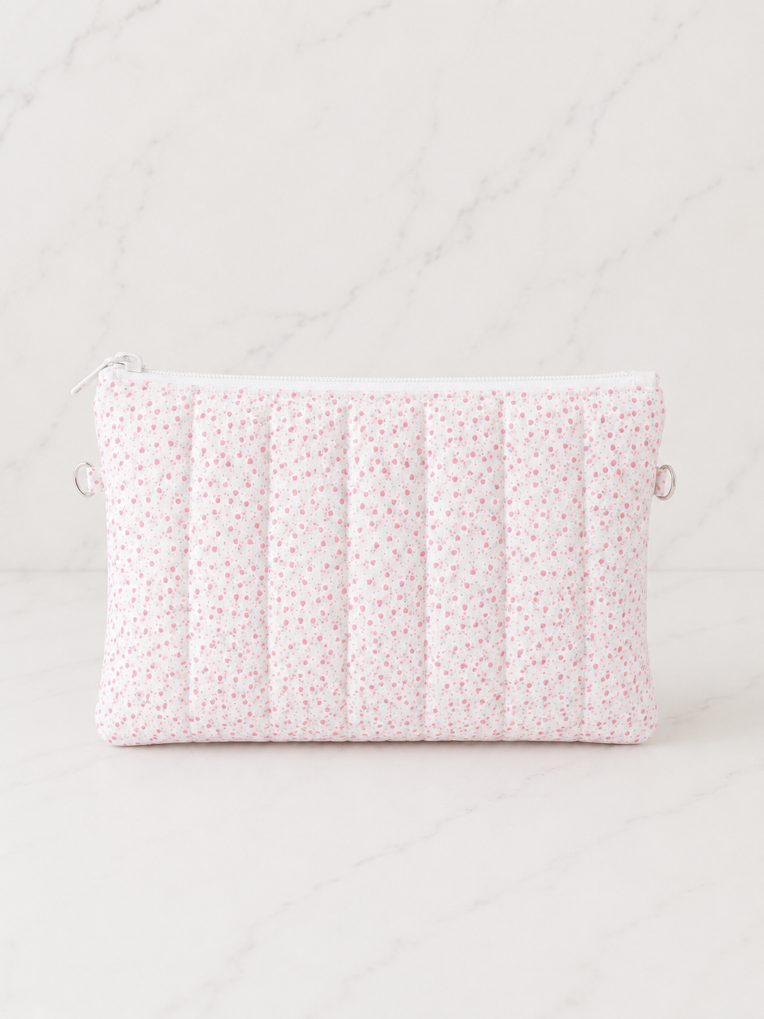 Pink floral quilted zipper pouch on soft white marble background in luxury studio lighting