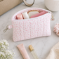 Pink floral quilted medium cosmetic pouch styled with beauty essentials and feminine neutral decor on marble surface