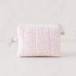 Pink floral quilted medium zipper pouch on luxury white marble background in clean editorial studio lighting