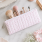 Pink floral quilted pencil case styled with makeup brushes and feminine beauty accessories on white marble countertop