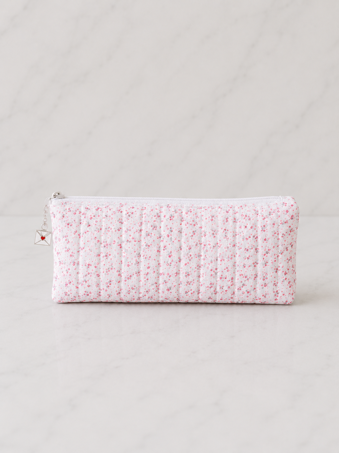 Pink floral quilted pencil case on white marble background in bright luxury studio lighting