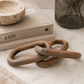 Rustic carved wood chain link decor styled in a California-modern editorial scene with travertine, smoked glass, and neutral layered textures.