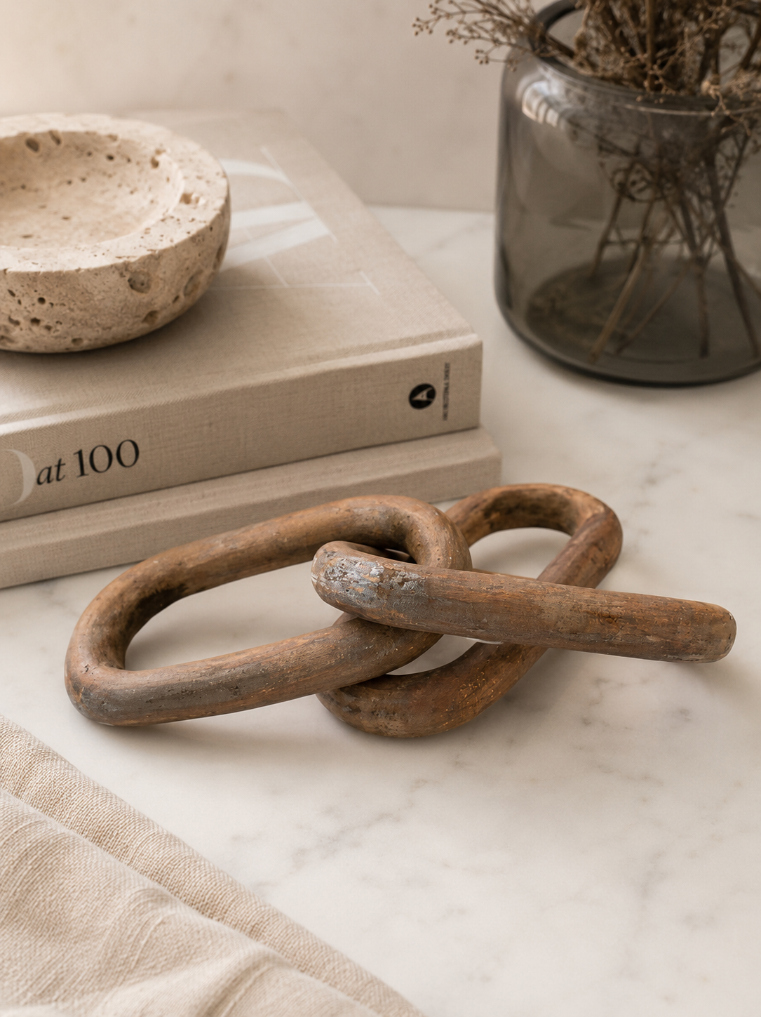 Rustic carved wood chain link decor styled in a California-modern editorial scene with travertine, smoked glass, and neutral layered textures.