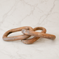 Rustic carved wood chain link decor styled on creamy ivory marble with a minimal luxury studio backdrop.