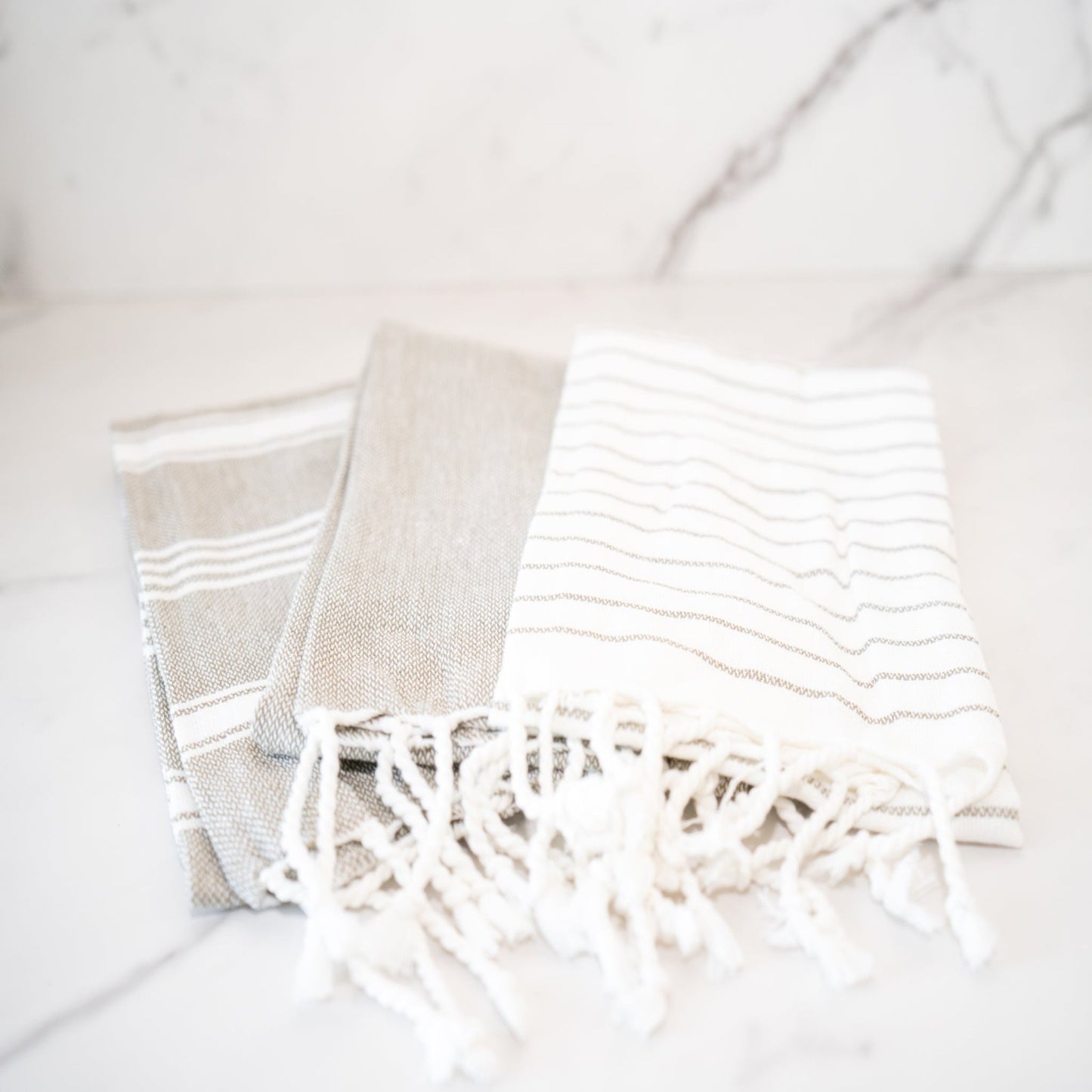 Set of gray and white textured tea towels with vibrant multicolor stripes, perfect for adding style and functionality to any kitchen.