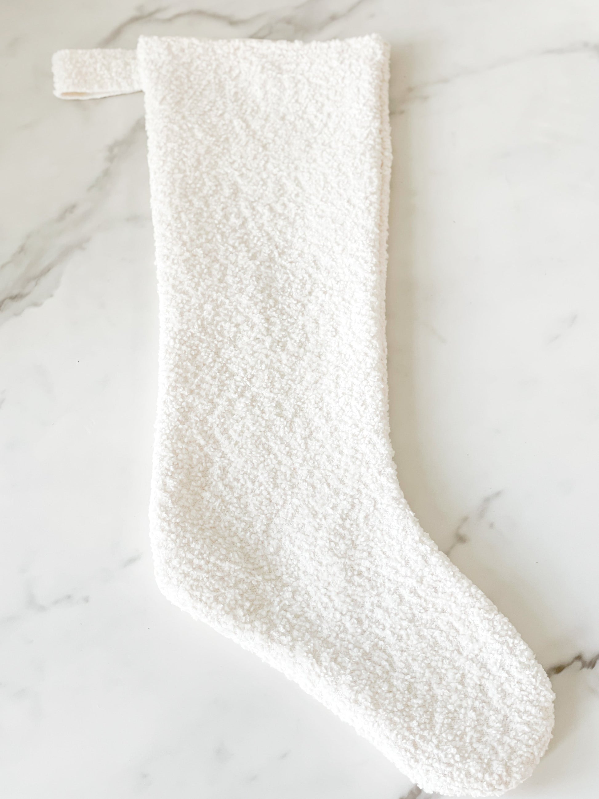 Close-up of white bouclé texture and cozy knit weave on holiday stocking